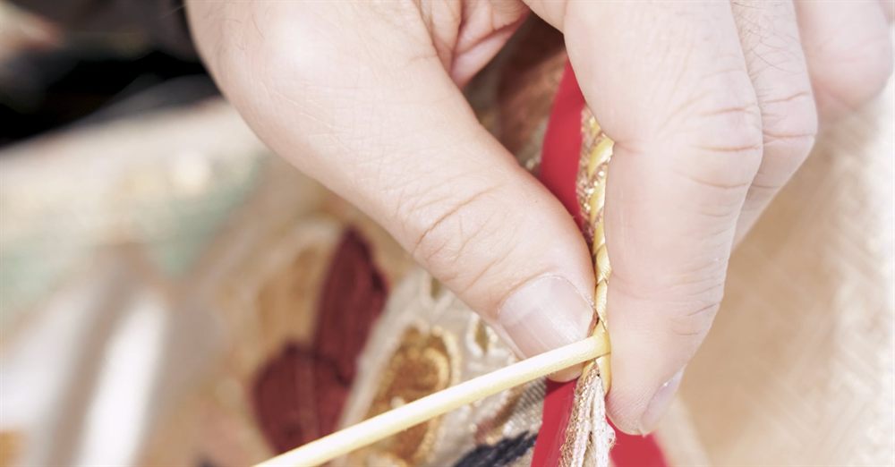 MIKOSHI Bag の縫製。赤と金の帯地の縁に、金の紐を縫い付ける手元
