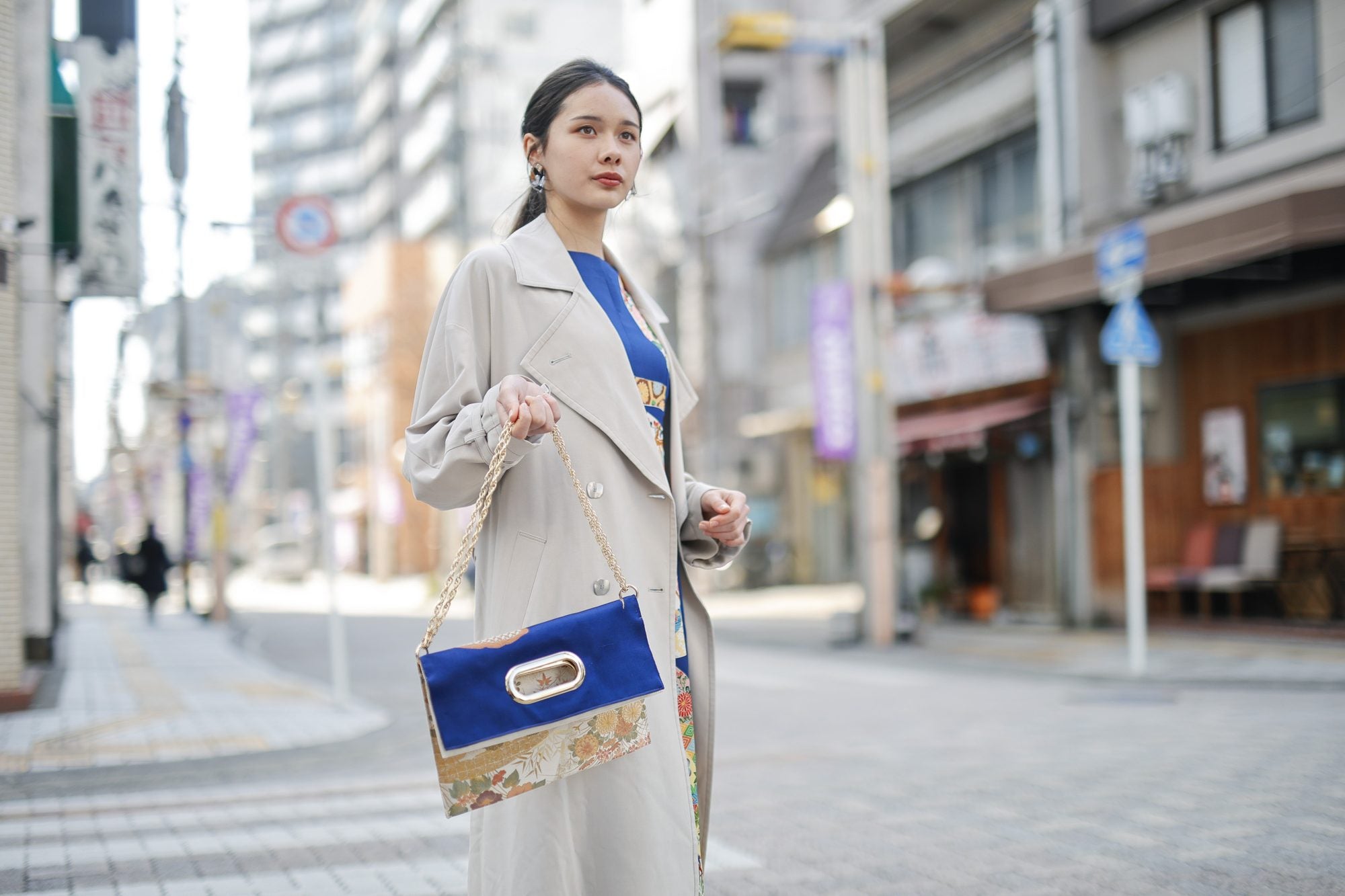 商店街で、OBI Bag のチェーンを手に提げる