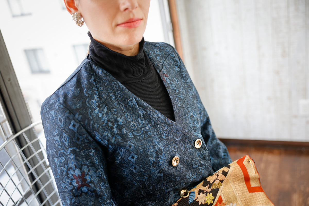 The neckline opens in a deep V, and an obi clutch shows at her lap.