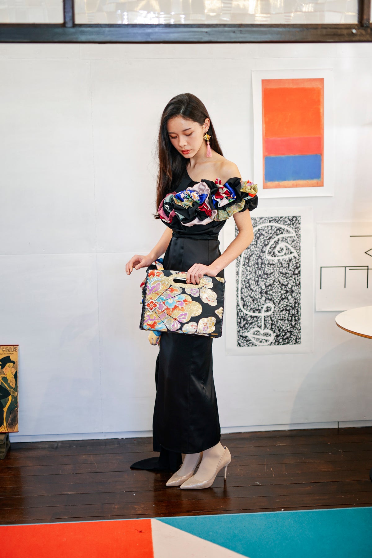 Held at the hip in one hand: a MIKOSHI Bag in black obi with flowers in many colours.