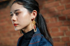 Hana-warabe earring with a red and white braided cord looped below the fitting