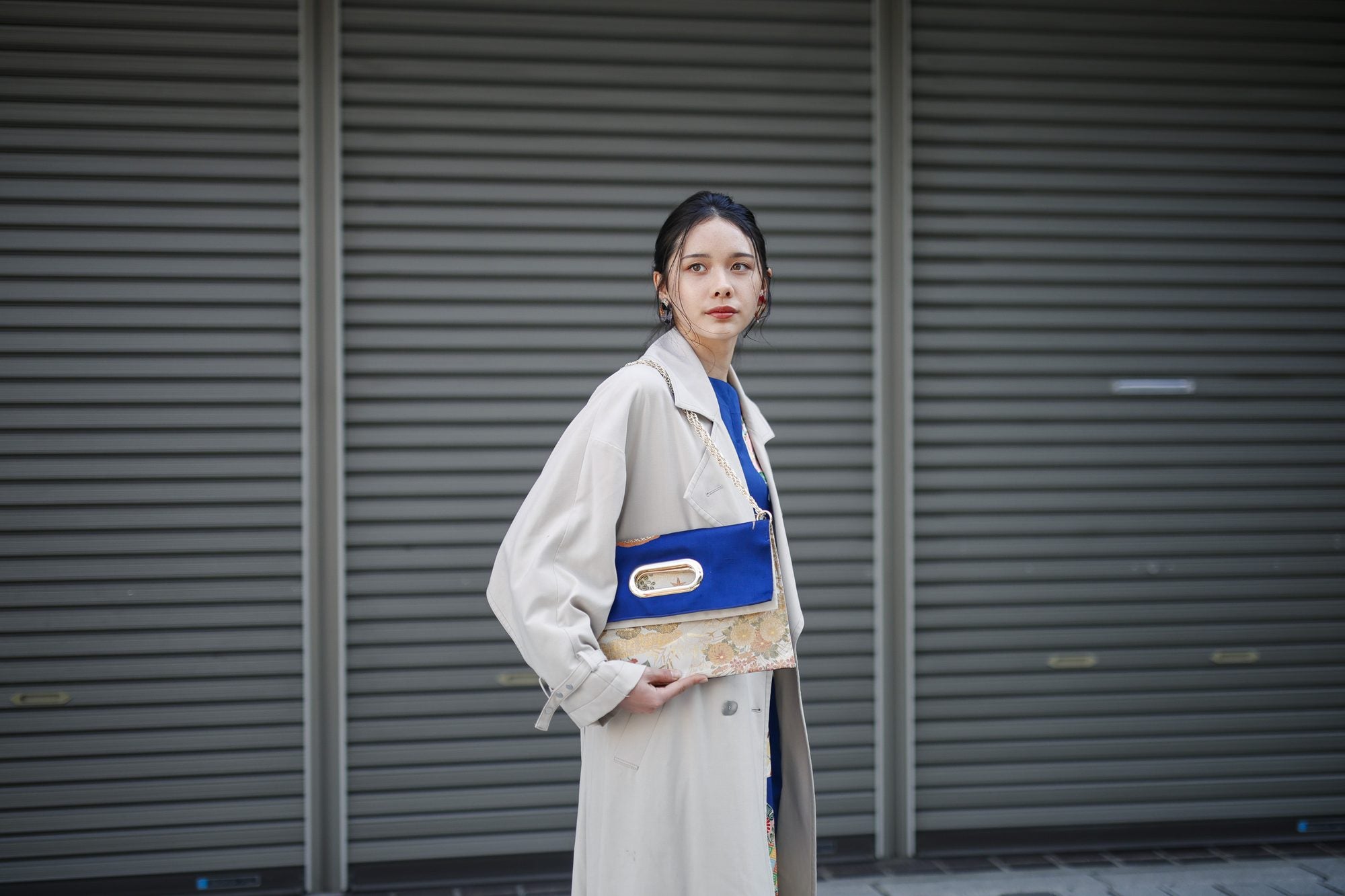 シャッターの前で、OBI Bag を肩に掛けて手を添える