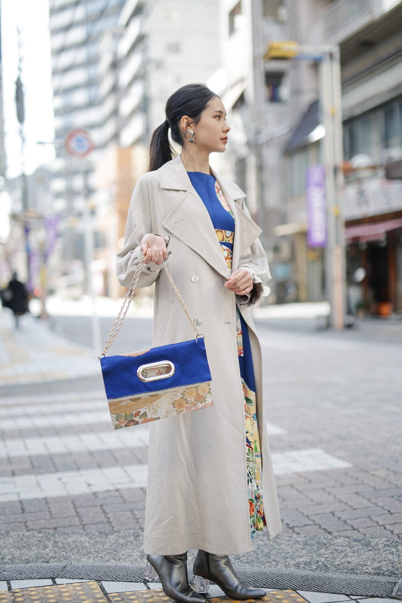 商店街を背に、OBI Bag をチェーンで提げた横顔