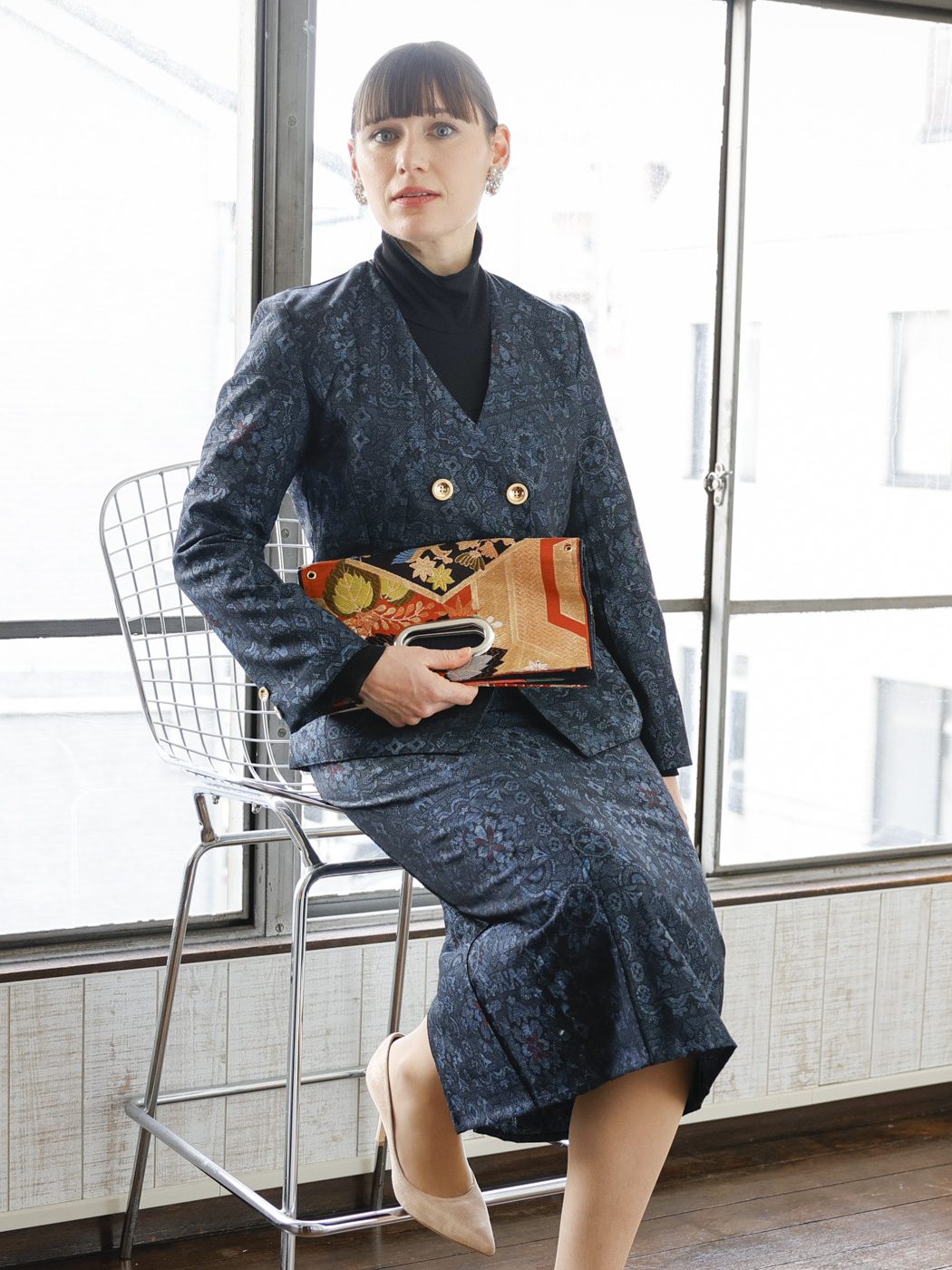 橙と黒の OBI Bag。折りたたんで脇に抱え、椅子に腰かける